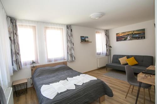 sypialnia z łóżkiem, kanapą i oknami w obiekcie Ormani Modern Stúdióapartman w mieście Pecz