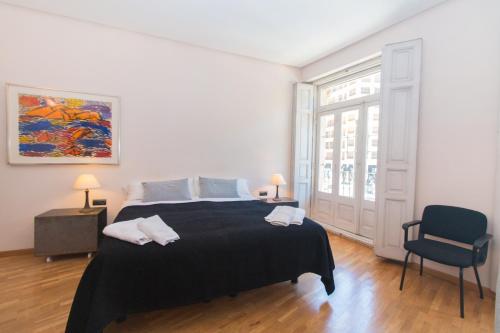 a bedroom with a large bed and a chair at Bet Apartments - Canovas rooms in Valencia