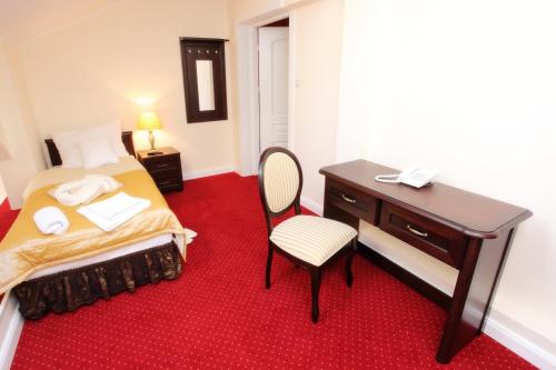a bedroom with a desk and a bed with a red carpet at Hotel Dwór Sójki in Sójki