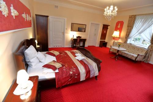 a bedroom with a large bed and a red carpet at Hotel Dwór Sójki in Sójki