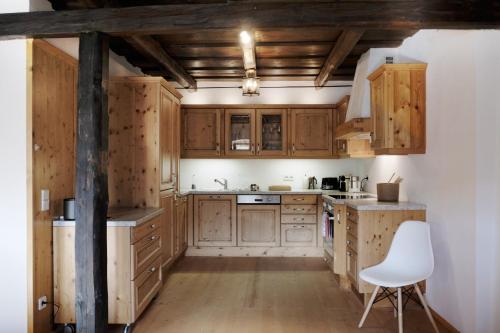 una cocina con armarios de madera y una silla blanca en Weinkellerurlaub Röschitz, en Roggendorf