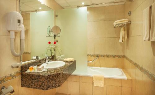 a bathroom with a sink and a bath tub at Golden Tulip Sharjah in Sharjah