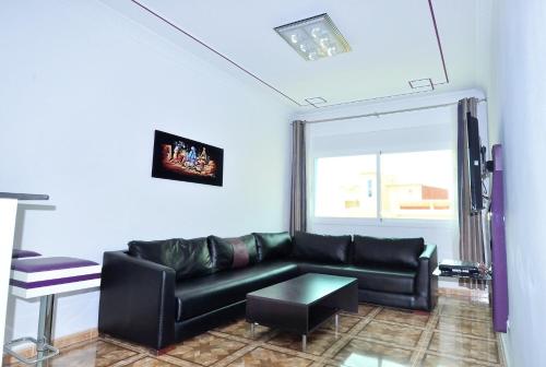 a living room with a black couch and a window at Appart Clim Wifi 700m de la Plage in Saidia 