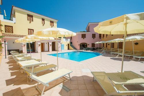 a pool with chairs and umbrellas next to a building at Residence Cala Viola in Cala Liberotto