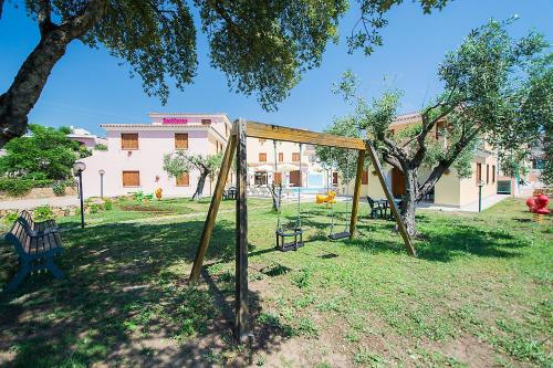a swing set in a yard with a building at Residence Cala Viola in Cala Liberotto