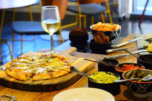 a table with a pizza and a glass of wine at Hougoumont Hotel Fremantle in Fremantle