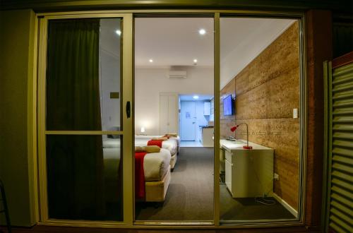 una camera con porta scorrevole in vetro che conduce a una camera da letto di Crossroads Ecomotel a Port Augusta
