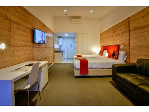 a hotel room with a bed and a desk and a couch at Crossroads Ecomotel in Port Augusta