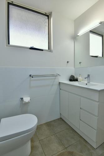 a white bathroom with a toilet and a sink at Crossroads Ecomotel in Port Augusta