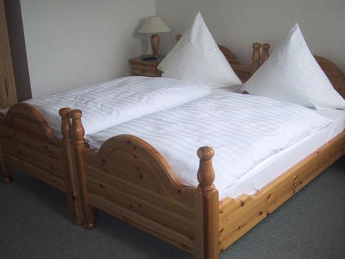 a large wooden bed with white sheets and pillows at Hotel Alt Wassenberg in Wassenberg