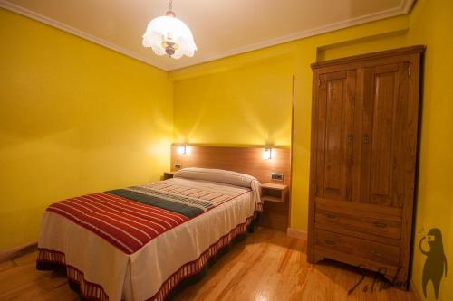 Dormitorio amarillo con cama y armario de madera en Casa Jauregui en Ibilcieta