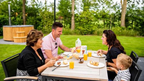 un grupo de personas sentadas en una mesa comiendo comida en TopParken – Résidence de Leuvert, en Cromvoirt