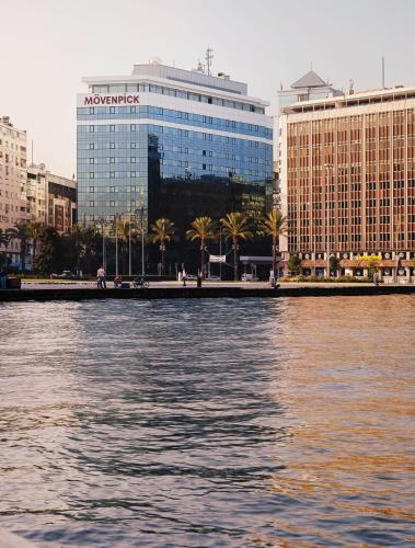 a body of water with buildings and palm trees at Mövenpick Hotel Izmir in Izmir
