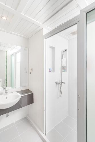 a white bathroom with a shower and a sink at Chayadol Resort - SHA Extra Plus in Chiang Rai