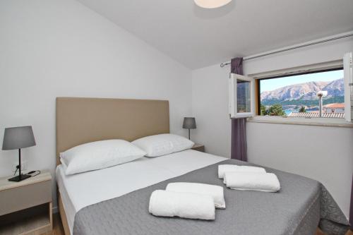 una camera da letto con un letto con due asciugamani bianchi di Sunshine Residence Baska a Baška