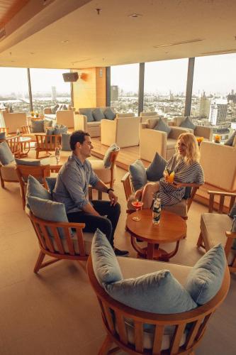 a man and woman sitting in chairs in a room at TMS Hotel Da Nang Beach in Da Nang