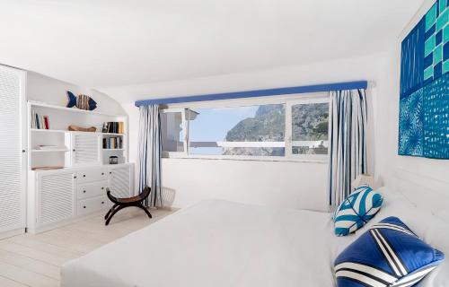 biała sypialnia z łóżkiem i oknem w obiekcie Villa Mariuccia Capri w mieście Capri