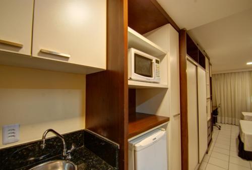 a small kitchen with a sink and a microwave at Ponta Negra Flats Partic in Natal