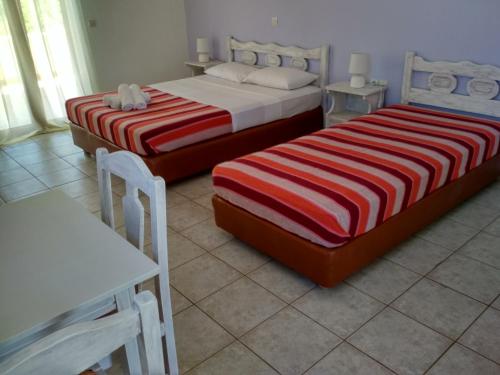 a bedroom with two beds and a table and a table at Skoutari Beach Hotel in Skoutari
