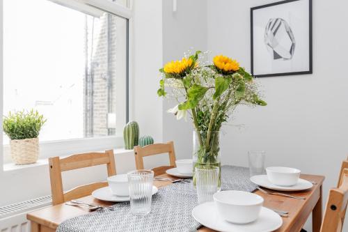 a dining room table with yellow flowers in a vase at WelcomeStay Clapham Junction 2 Bedroom Apartment in London