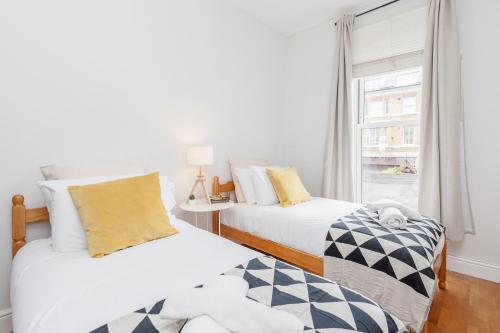 two beds in a room with a window at WelcomeStay Clapham Junction 2 Bedroom Apartment in London
