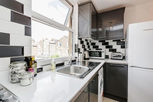 a kitchen with a sink and a refrigerator at WelcomeStay Clapham Junction 2 Bedroom Apartment in London