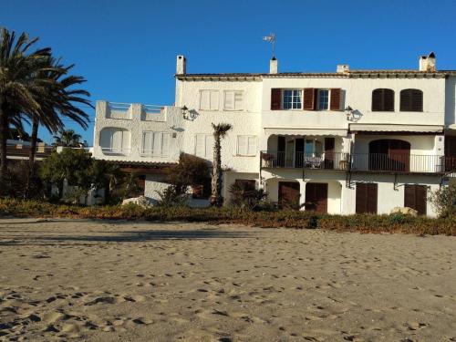 a white house on the beach with palm trees at Paraiso frente al mar Apto duplex in Comarruga