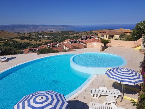 a swimming pool with two umbrellas and two chairs and a swimming pool at Residence Pala Stiddata with panoramic swimming pool in Trinità d'Agultu e Vignola