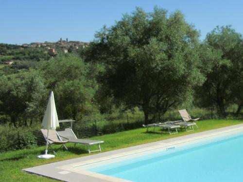 a pool with two chairs and a table and a umbrella at Agriturismo La Torretta in Siena