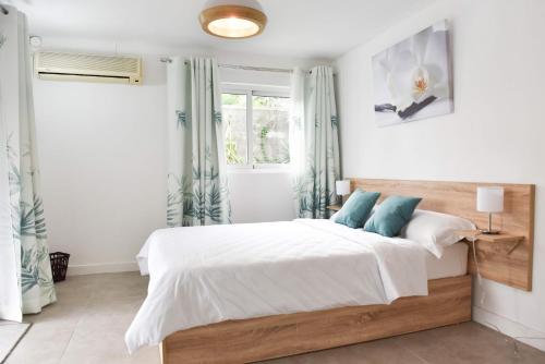 a bedroom with a bed with white sheets and blue pillows at Tamarin Chambres d'Hotes in Tamarin