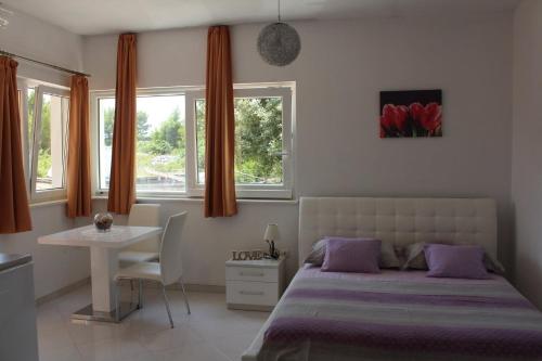 1 dormitorio con cama, mesa y ventanas en Apartments Tomo, en Hvar