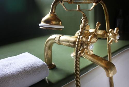 a bathroom sink with a brass faucet and a towel at Chateau LE BROSSAY in Renac