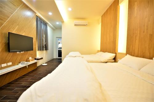 a hotel room with two beds and a flat screen tv at 日晴民宿 Sun Day in Magong