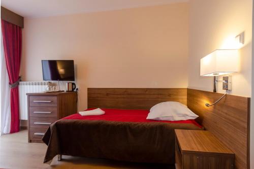 a bedroom with a bed with a red blanket and a television at Sanatorium Energetyk in Krynica Zdrój