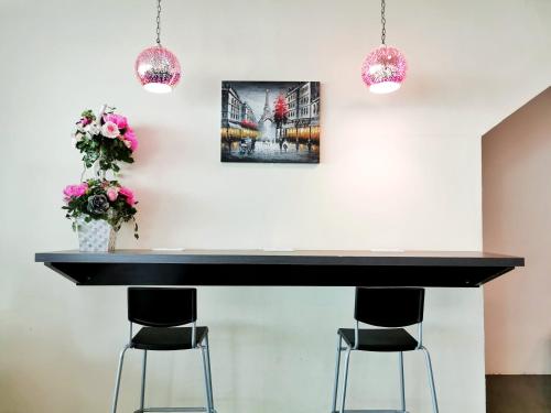 a black table with two stools and two pictures on the wall at Merilton Hotel in Sungai Petani
