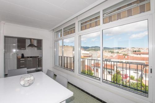 a dining room with a white table and large windows at Apartamentos Costa Brava Las Vistas in Sant Feliu de Guíxols