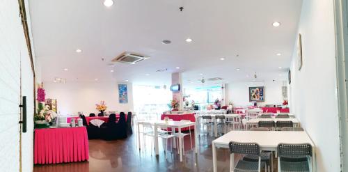 a restaurant with white tables and red chairs at Merilton Hotel in Sungai Petani