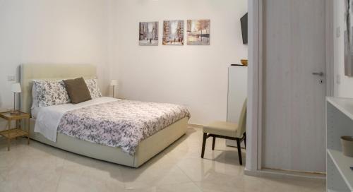 a white bedroom with a bed and a chair at La Dolce Vita in Potenza