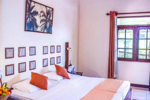 1 dormitorio con 1 cama blanca grande con almohadas de color naranja en Insight Resort Ahangama - S&S Other Certified, en Ahangama