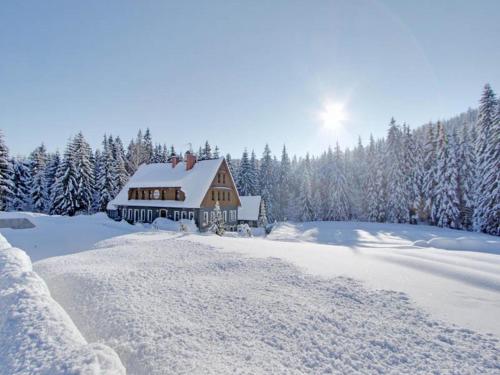 a house covered in snow with trees in the background at Hotel Perla Jizery in Josefuv dul