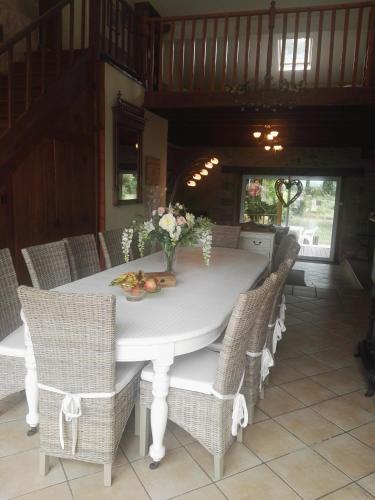 a white dining room table with wicker chairs at Le Chene Vert in Millac