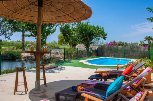 een groep stoelen en een parasol naast een zwembad bij Paradise Ebro 2 in Deltebre