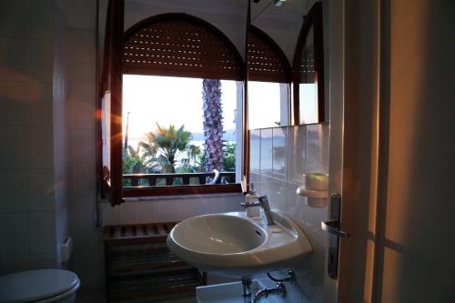 een badkamer met een wastafel, een spiegel en een raam bij Eliton in Alghero