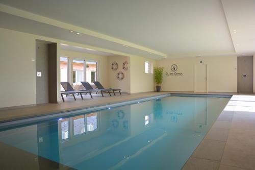 a large swimming pool with two chairs in a room at Duins Genot 5 star Holiday Homes 30p & 40p - Indoorpool & Wellness in Jabbeke