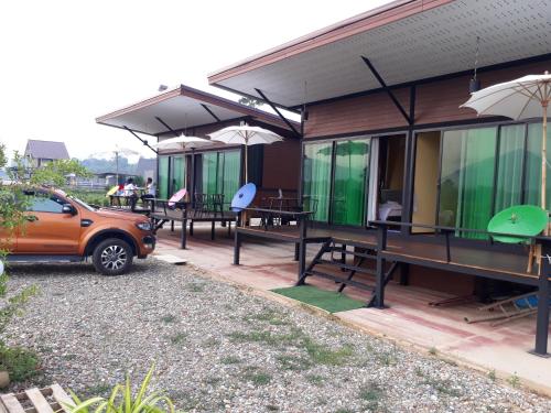 a house with tables and chairs and a car parked outside at บวกบัววิวรีสอทร์ in Nan