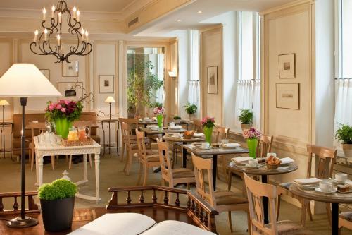 un restaurant avec des tables, des chaises et un lustre dans l'établissement Hôtel De l'Arcade, à Paris