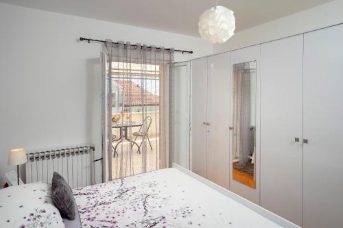 a white bedroom with a bed and a window at Apartments Roso - ZF Hvar in Hvar