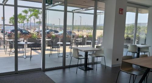 a restaurant with tables and chairs and glass windows at Tramuntana in La Jonquera