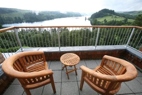 two chairs and a table on a balcony with a view at Lake Vyrnwy Hotel & Spa in Llanwddyn