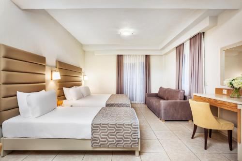 a hotel room with two beds and a couch at Poseidon Palace in Leptokaria